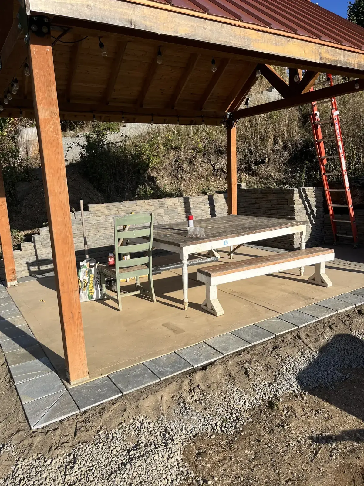 Inside a timber pavilion with a stone floor, a table and benches